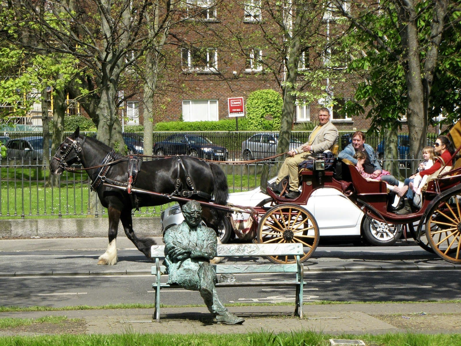 Horse-drawn carriage passing the Patrick Kavanagh statue by the Grand Canal